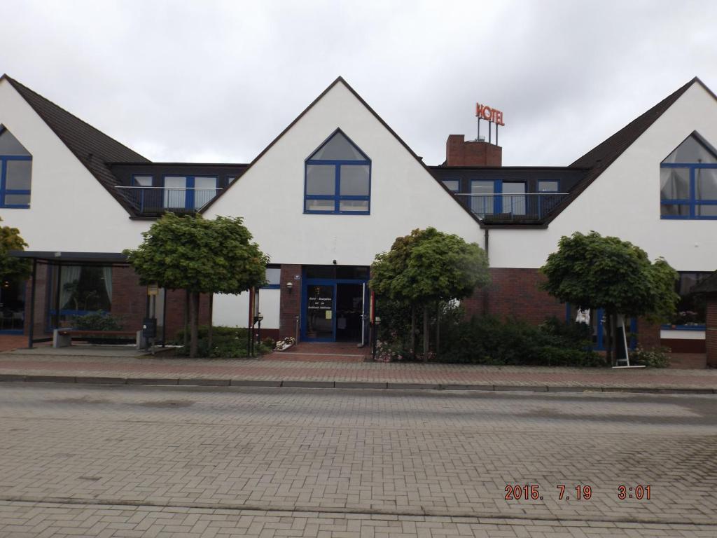 a white building with blue windows on a street at Hotel Ziegenkrug Schweriner Tor in Pampow