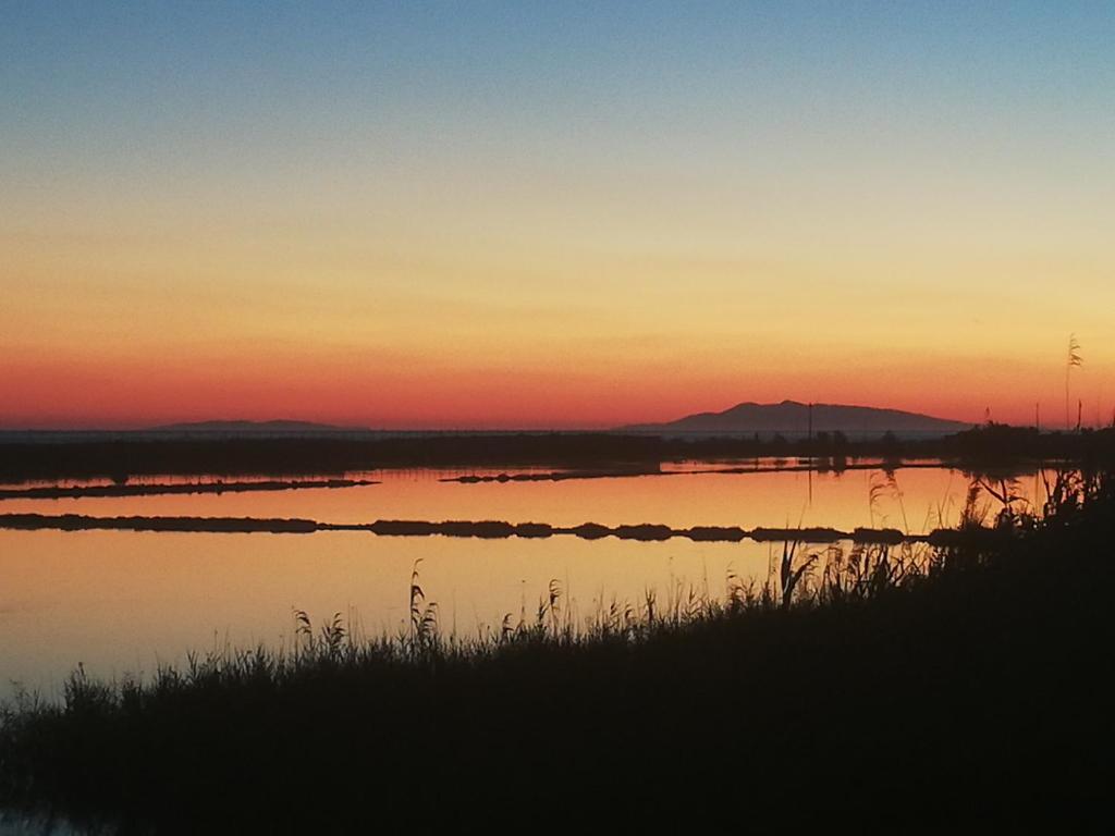 a sunset over a body of water with a mountain in the background at Appartamento vista mare Tarquinia in Tarquinia