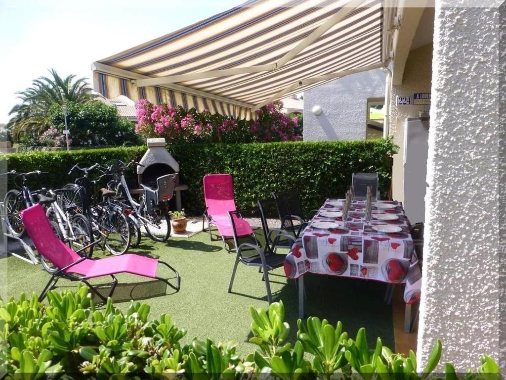 a table with pink chairs and a bunch of bikes at Hameau du Rivage 224 - Rez de jardin climatisé - 3 étoiles - 6 Pers - Jardin - Piscine - Vélos prêtés - Parking - 400m de la plage de La Lagune - WIFI in Saint-Cyprien