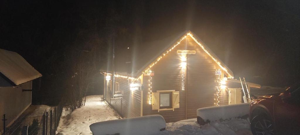 a wooden house with lights on it in the snow at Pan Modrzew in Zachełmie