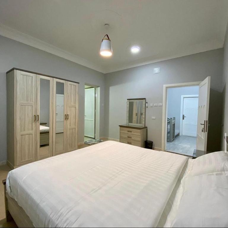 um quarto com uma grande cama branca e um espelho em فيلا 109 الطائف الشفا em Al Shafa
