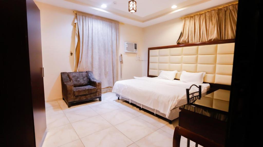 a hotel room with a bed and a chair at Ru'a Al Qunfudhah Furnished Units in Al Qunfudhah