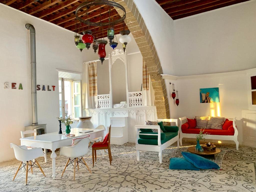 a living room with a table and chairs and a couch at seasalthouse - famous tv location in Koskinou