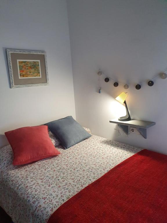una camera da letto con un letto con un cuscino rosso e una lampada di Casco histórico- Vivienda de 2 habitaciones a Oviedo