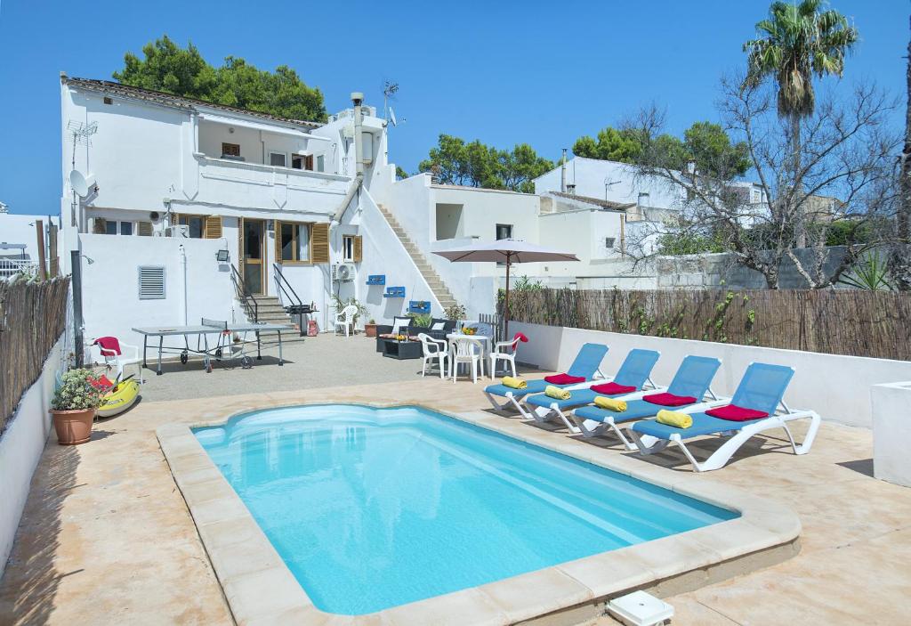 einen Pool mit Stühlen, einen Tisch und ein Haus in der Unterkunft Owl Booking Villa Trinxater - 12 Min Walk to the Beach in Alcúdia