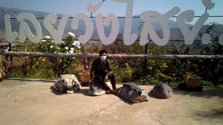 a man wearing a mask sitting in front of a sign at รี่สอตน้ำตกถ้ำพระ in Ban Non Sung