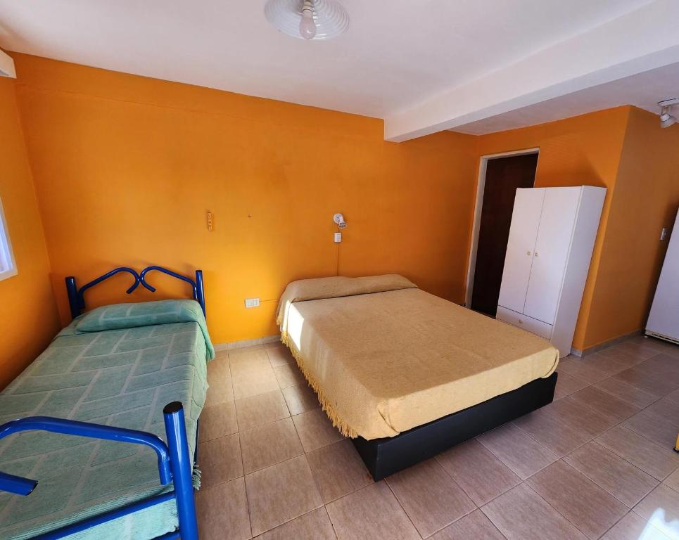 two beds in a room with orange walls at Complejo Mayu Inti Wayra - Mayu Sumaj in Villa Icho Cruz