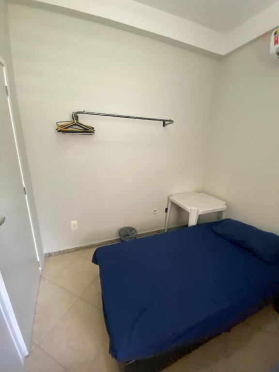 a room with a blue bed and a shelf on the wall at Hostel Concordia/Nova floresta in Belo Horizonte