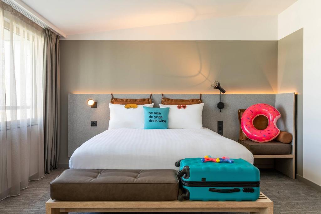 a hotel room with a bed with luggage on it at Moxy Bordeaux in Bordeaux