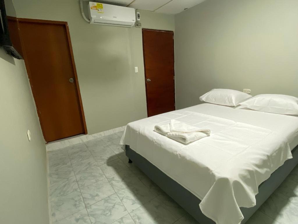 una camera da letto con un grande letto con lenzuola e cuscini bianchi di HOSTAL CASA PALMA a Ríohacha