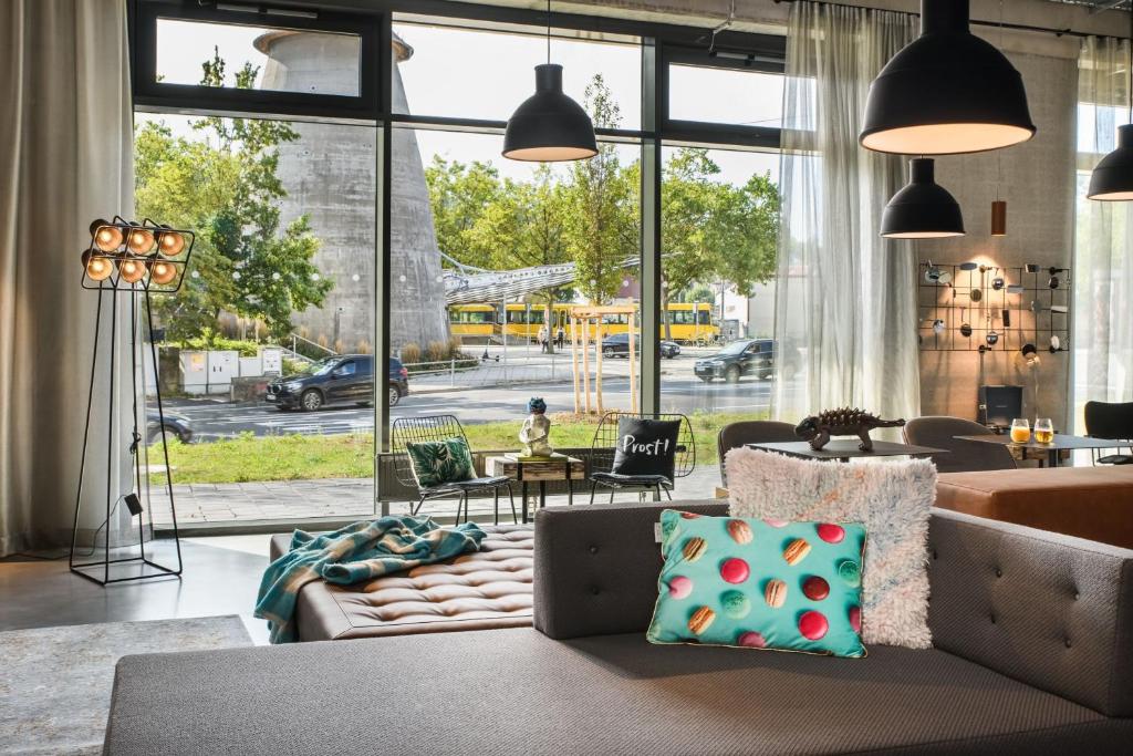 a living room with a couch and a large window at Moxy Stuttgart Feuerbach in Stuttgart