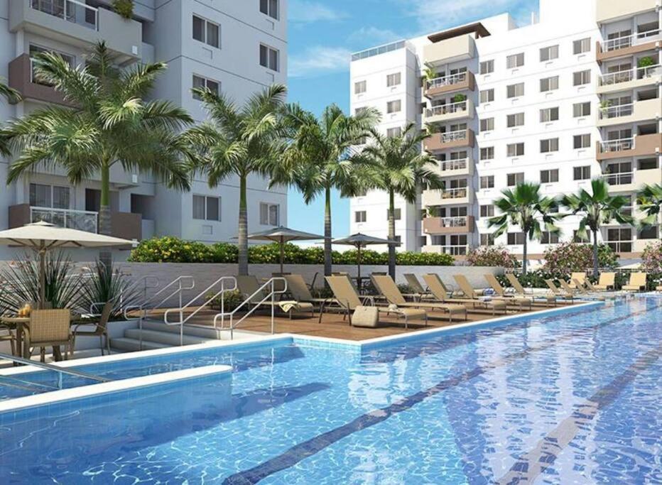 a swimming pool at a resort with chairs and palm trees at Excelente apartamento a 5 minutos da praia e shopping in Rio de Janeiro