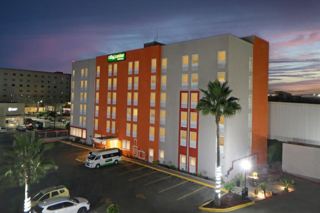 un bâtiment d'hôtel avec des voitures garées dans un parking dans l'établissement City Express Junior by Marriott Tijuana Otay, à Tijuana