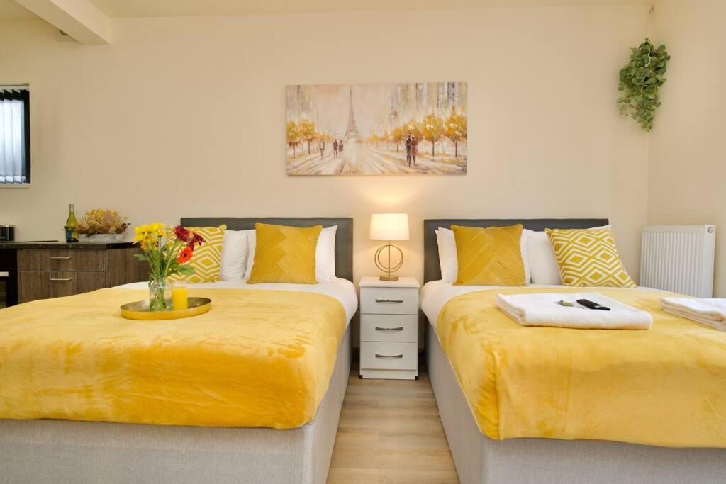 Duas camas com lençóis amarelos num quarto em Matlock Studio 2 – Coventry em Coventry