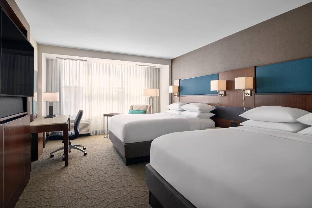 a hotel room with two beds and a desk at Delta Hotels by Marriott Milwaukee Northwest in Menomonee Falls