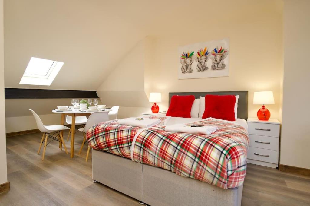 a bedroom with a bed with red pillows and a table at Matlock Studio 5 - Coventry in Coventry