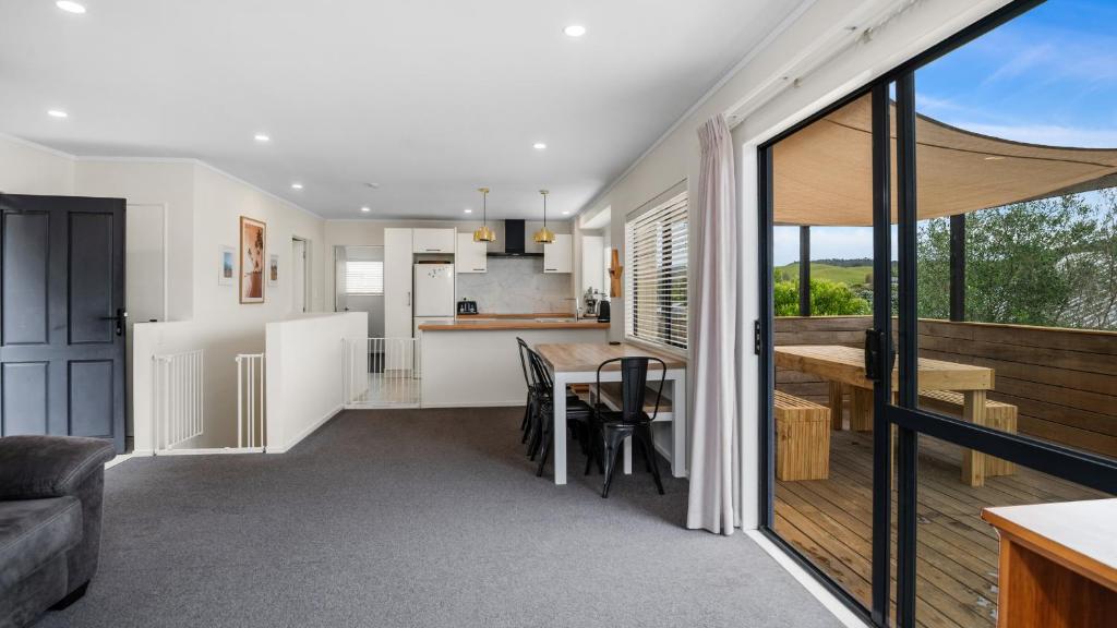 a kitchen and living room with a table and a kitchen and a dining room at Hibiscus Hideaway - Orewa Beach Holiday Home in Orewa