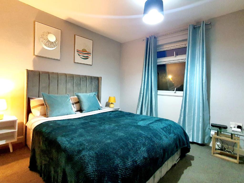 a bedroom with a large bed and blue curtains at Serviced Accommodation near London and Stansted - 2 bedrooms  in Harlow