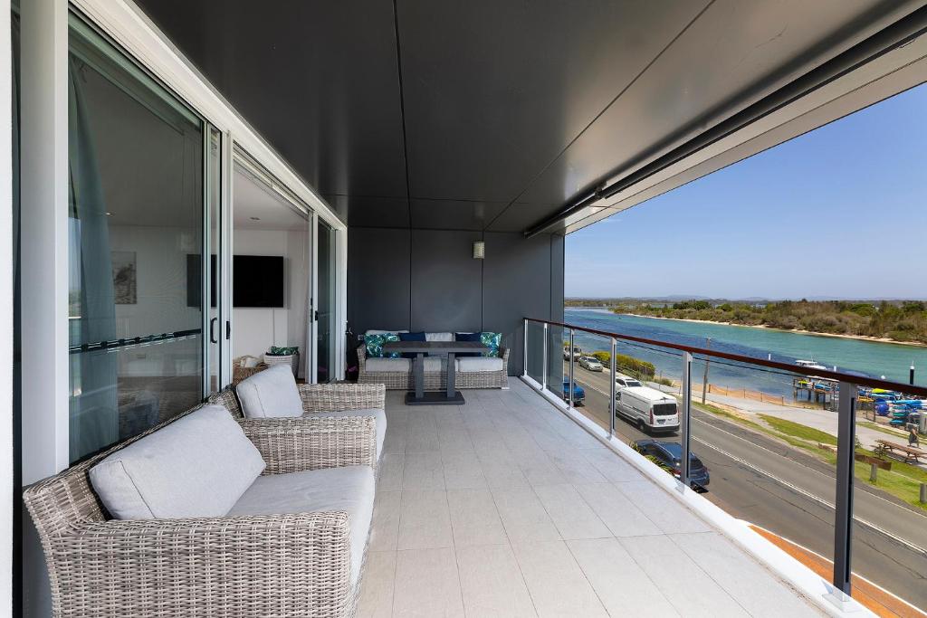 balcón con sillas de mimbre y vistas al océano en Waterline 302, en Forster