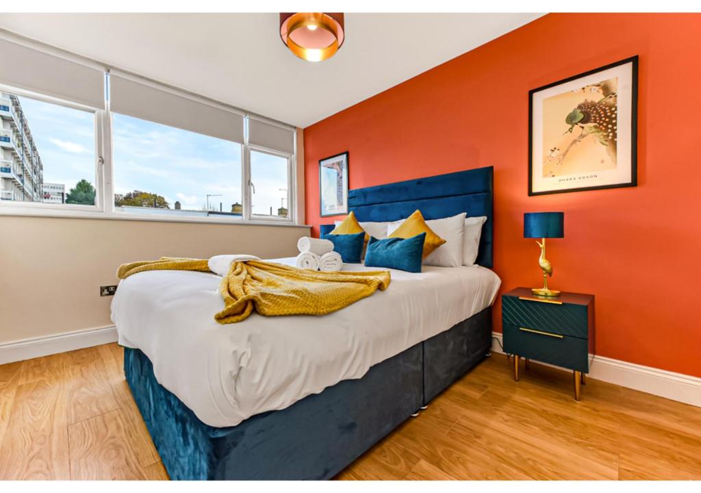a bedroom with a large bed with an orange wall at Stunning Family Home - Sleeps 11 in London