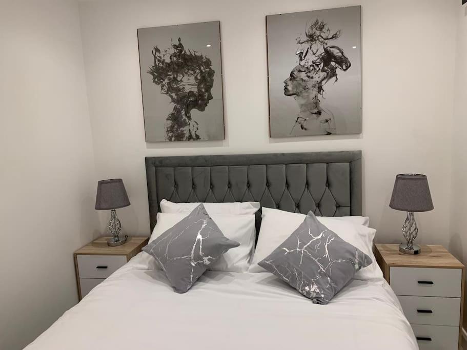 a bedroom with a bed with pillows and two lamps at Apartment C, a one bedroom Flat in south London in Carshalton