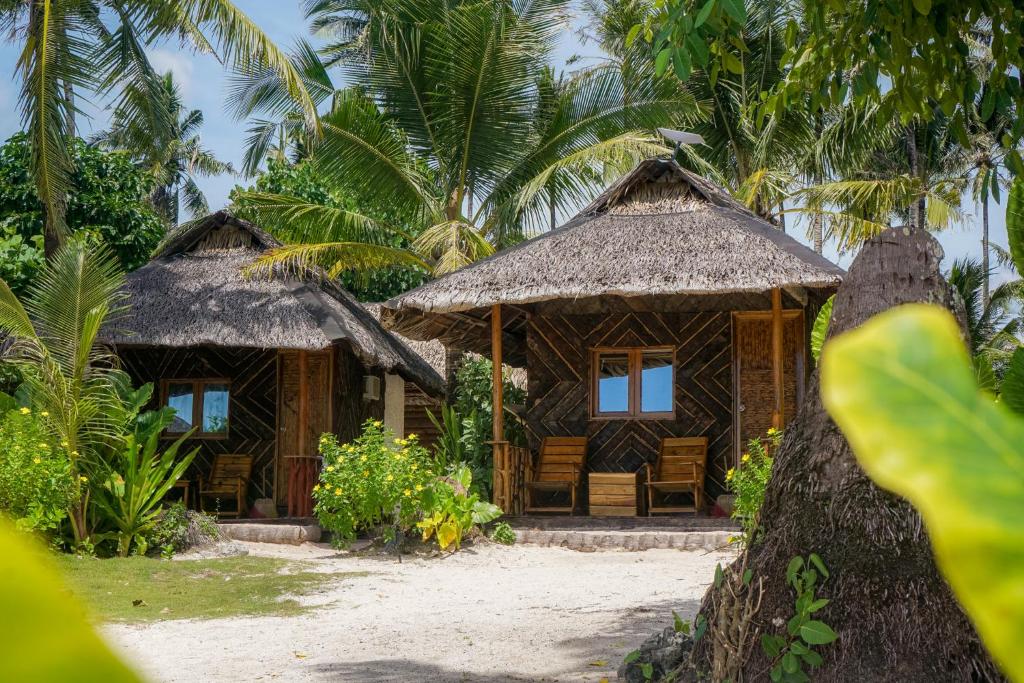 two huts on a beach with palm trees at Marahuyo Siargao in Catangnan