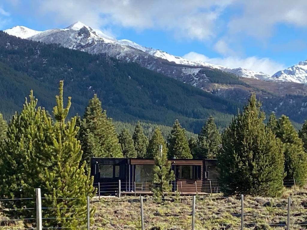 uma casa no meio de uma floresta com uma montanha em Meliquina Home em Villa Meliquina