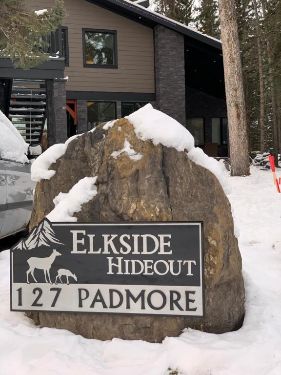 a sign on a rock in the snow next to a house at Romantic Luxury Retreat with Private Sauna & Spa, Pet Friendly, Elkside Hideout B&B in Canmore