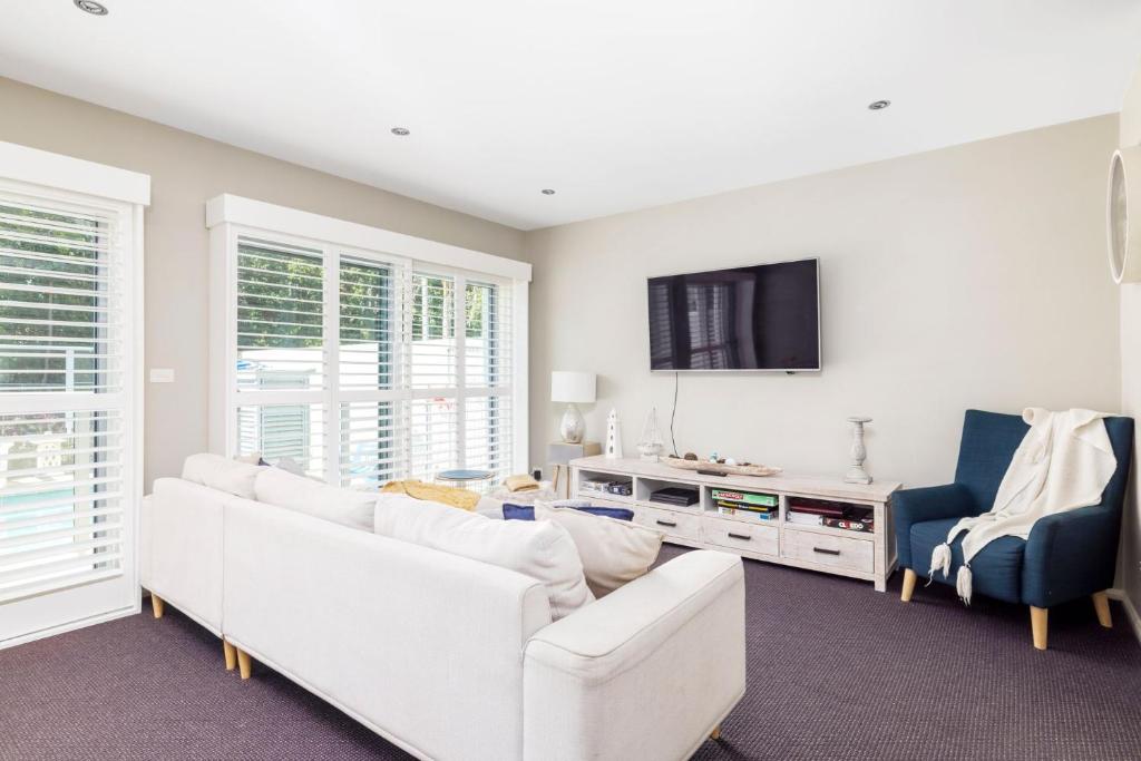 ein Wohnzimmer mit weißen Möbeln und einem Flachbild-TV in der Unterkunft 514 Oaks Pacific Blue Townhouse in Salamander Bay
