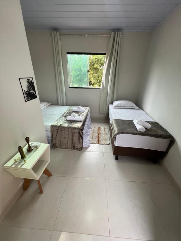 - une chambre avec 2 lits, un lavabo et une fenêtre dans l'établissement Hospedaria Villa dos Ventos, à Itaúnas