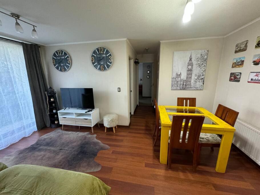 a living room with a yellow table and a television at Departamento Park Collao Suit - Empresas Factura - Parking - wifi in Concepción
