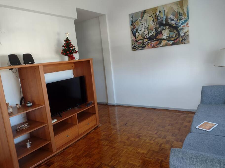 uma sala de estar com televisão e um sofá azul em Nico Home Baires - Departamento grande a estrenar em Buenos Aires