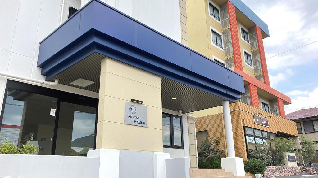 a building with a blue canopy on the front of it at Global Resort ONO de LUNE in Hatsukaichi