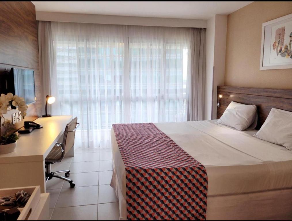 een slaapkamer met een bed, een bureau en een raam bij Hotel Vision in Brasilia