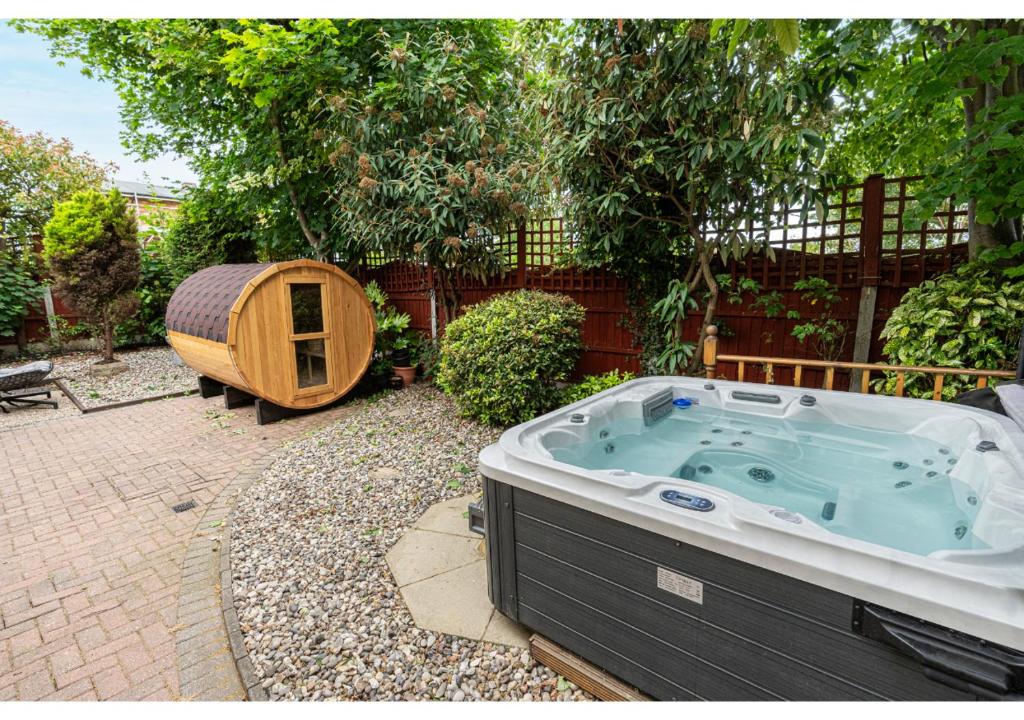 a jacuzzi tub in a yard with a fence at Nature's Serenade:3BR Classic Home-Jacuzzi & Sauna in Canvey Island