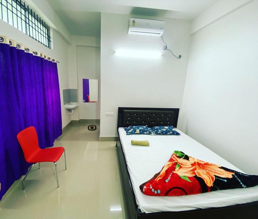 a bedroom with a bed and a red chair at Hotel Abhinov in Dibrugarh