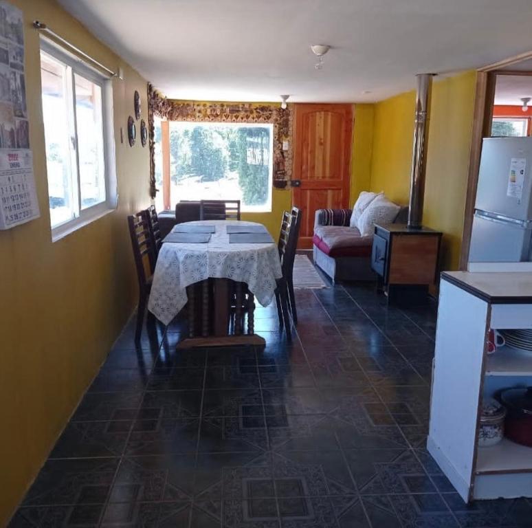 a kitchen and dining room with a table and a couch at Cabañas Icalmahuida in Icalma