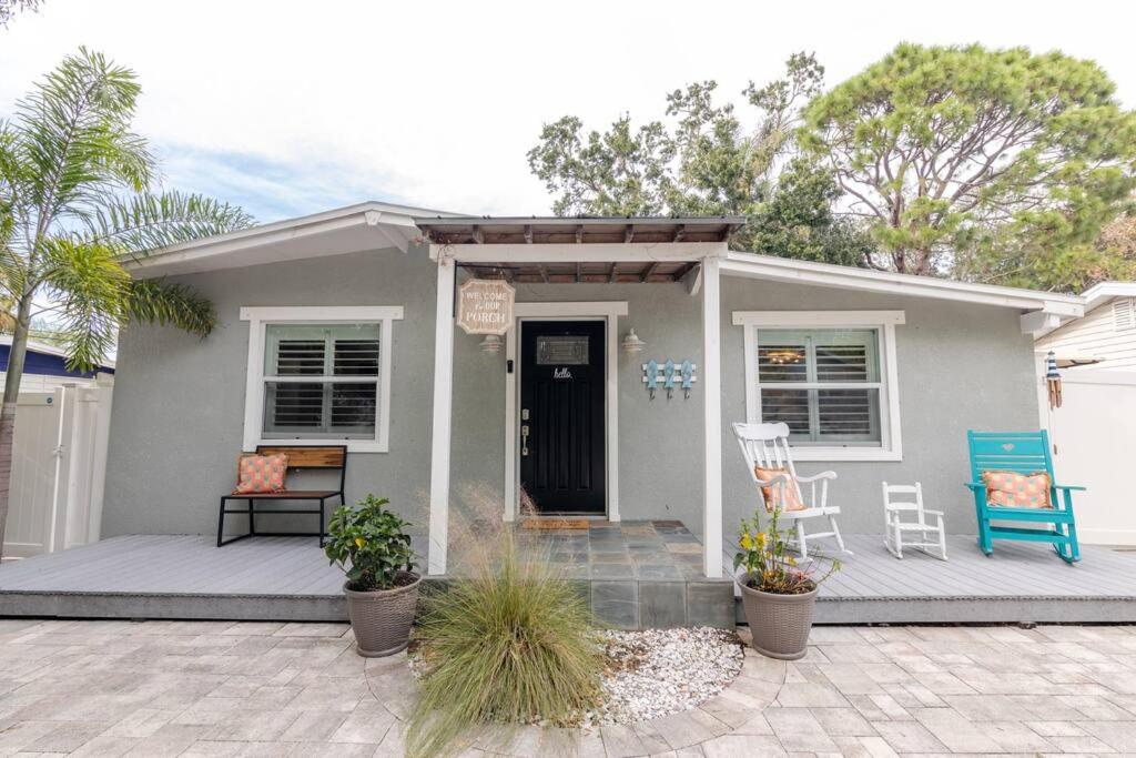 uma pequena casa cinzenta com uma cadeira azul em frente em Happy Camper Cottage - Cozy Oasis with Hot Tub em Palm Harbor