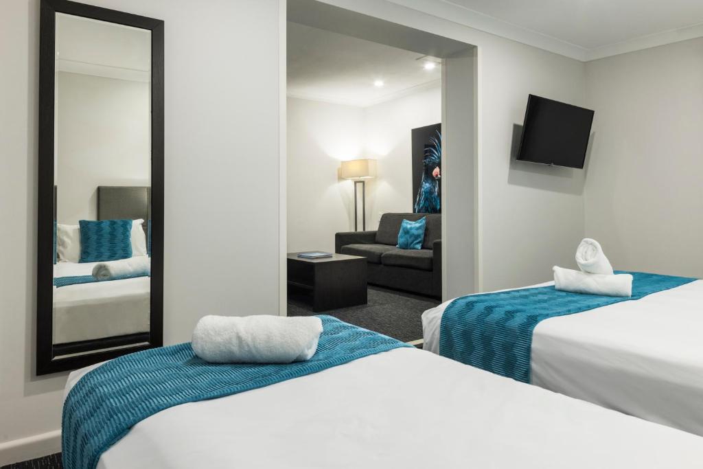 a hotel room with two beds and a mirror at The Abbott Boutique Hotel in Cairns