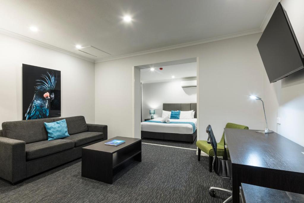 a living room with a couch and a bed at The Abbott Boutique Hotel in Cairns