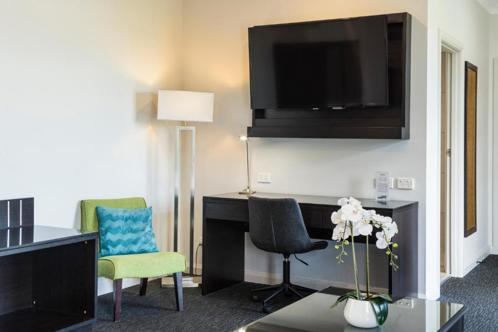 a hotel room with a desk and a flat screen tv at The Abbott Boutique Hotel in Cairns