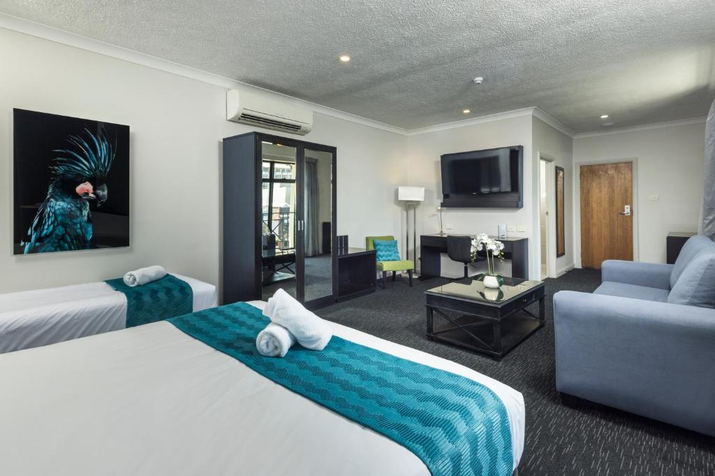 a hotel room with two beds and a living room at The Abbott Boutique Hotel in Cairns