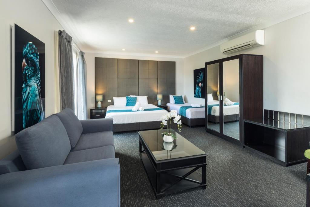 ein Hotelzimmer mit einem Sofa und 2 Betten in der Unterkunft The Abbott Boutique Hotel in Cairns