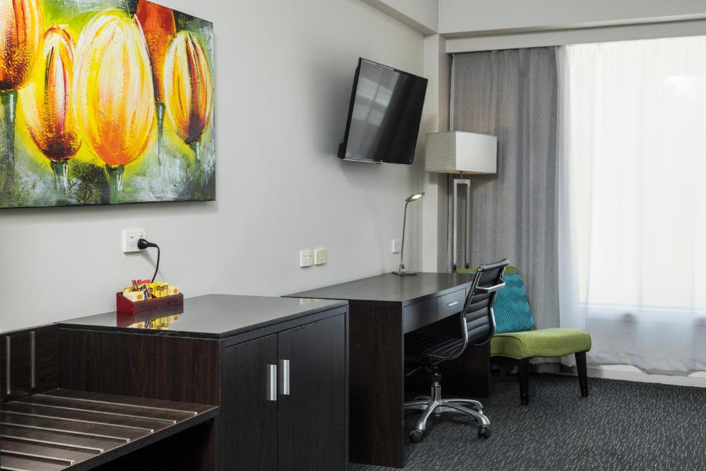 a hotel room with a desk and a tv at The Abbott Boutique Hotel in Cairns