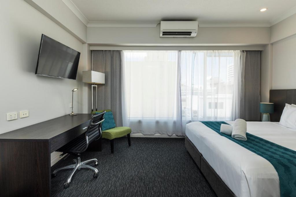a hotel room with a bed and a desk at The Abbott Boutique Hotel in Cairns