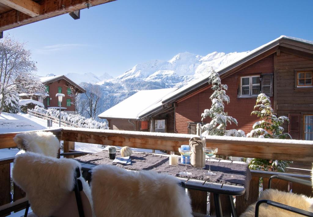 a deck with a table and chairs in front of a house at Chalet Sole in Wengen