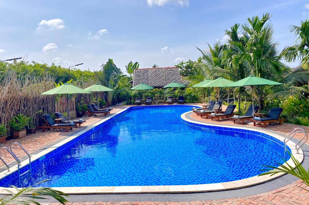 einen Pool in einem Resort mit Stühlen und Sonnenschirmen in der Unterkunft MEKONG SILT ECOLODGE in Cần Thơ