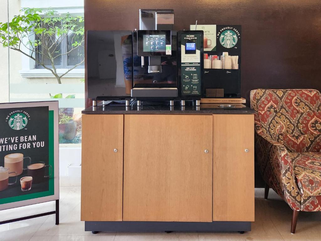 A self-service coffee station with an automatic espresso machine and one lounge chair.