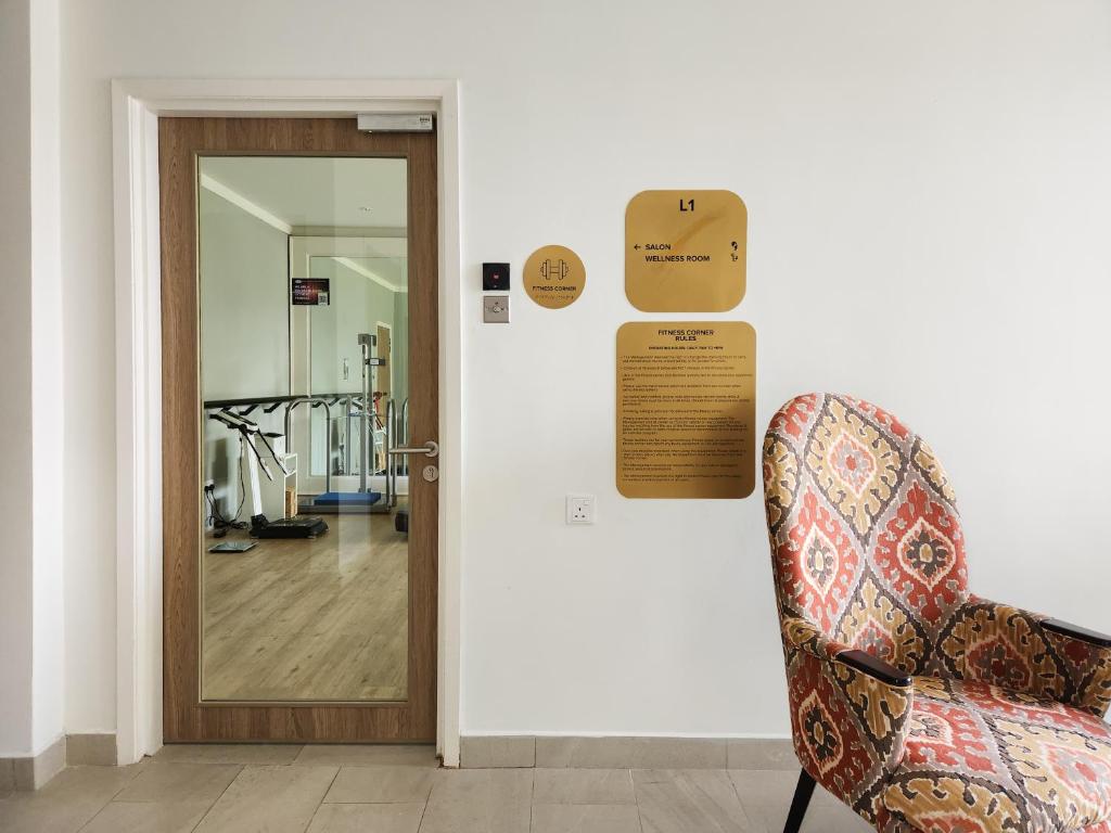 A corridor entrance with a mirrored door, directional plaques and a patterned chair.