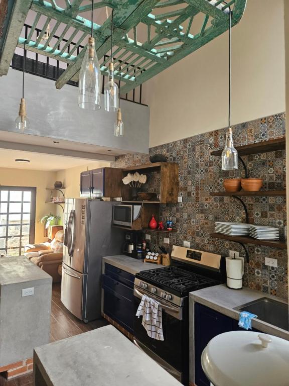 a kitchen with a stove and a refrigerator at Loft Candelaria Pacaya in Antigua Guatemala